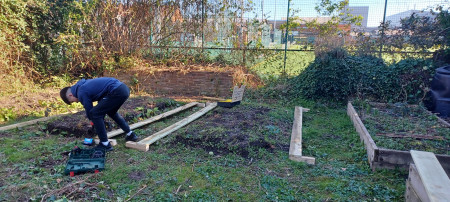 Student using tools and putting together a raised garden bed.