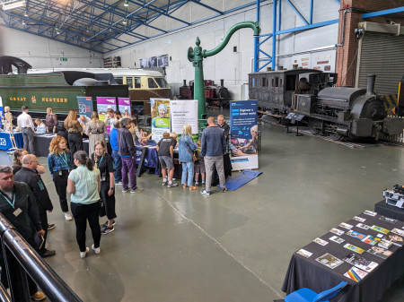 View of employer stands in the Great Hall of the National Railway Museum, with trains in the background.