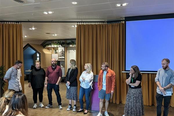 A group of 8 staff members stood in a line in front of a group of young people